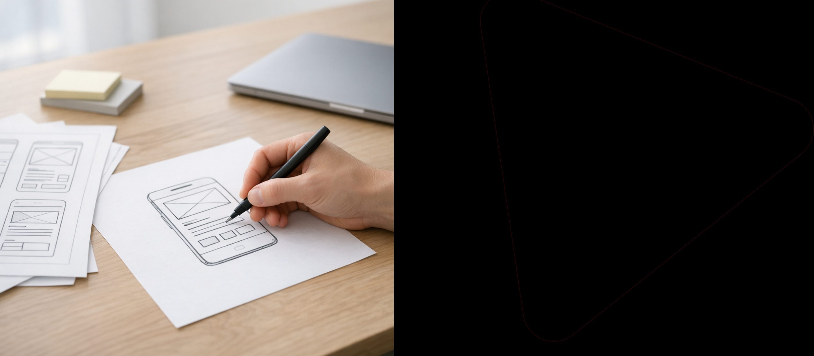 A hand sketching a mobile app wireframe on a desk in a design studio